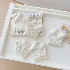 Detail of cream white cotton socks with lace edges and heart cutout mesh texture