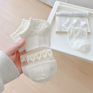 Macro detail of white mesh socks featuring heart lace embroidery and ruffled edges