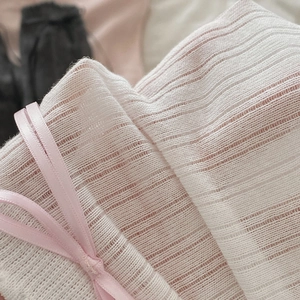 Detail of pink knit socks featuring ribbed texture and elegant satin ribbon bow detail