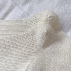 Detailed close-up of cream-colored rib-knit socks showing the soft vertical texture and stitching