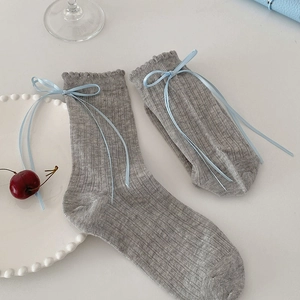Detail of grey ribbed knit socks with light blue satin bows and wavy scalloped edges