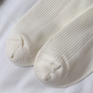 Close-up of white ribbed knit socks showing vertical texture and seamless toe stitching