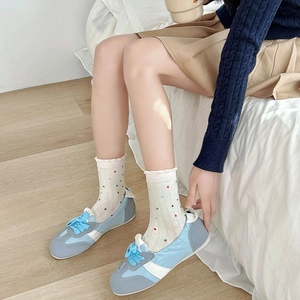 Detalle de calcetines con lazo rosa y blanco con zapatillas azules en un estilo acogedor