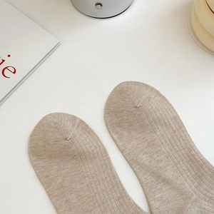 Close-up of beige ribbed knit knee-high socks showing textured weave and premium cotton fabric