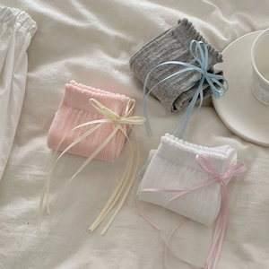 Close-up of ribbed cotton socks featuring silk ribbons and frilled cuffs in three soft colors