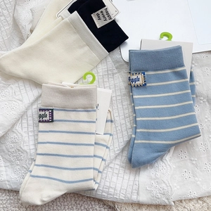 Flat lay detail of blue striped and solid cotton socks with embroidered cloth labels