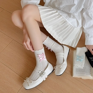 Détail de chaussettes blanches ondulées à nœuds roses avec des chaussures Mary Jane