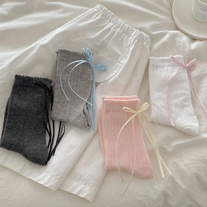 Detail of four cotton ribbon bow socks in black grey pink and white with textured ribbing