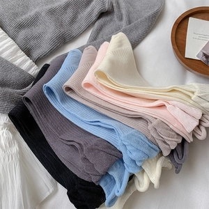 Close-up of colorful ribbed knit socks in pastel tones stacked on textured white fabric
