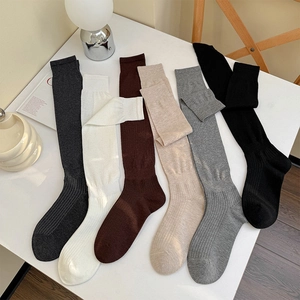 Close-up of six pairs of multi-color ribbed knee-high socks laid out on a white desk
