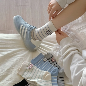 Close-up of striped cotton mid-calf socks with small fabric label in a cozy bedroom setting