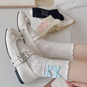 Détail de chaussures Mary Jane blanches avec rubans et chaussettes jacquard à nœuds
