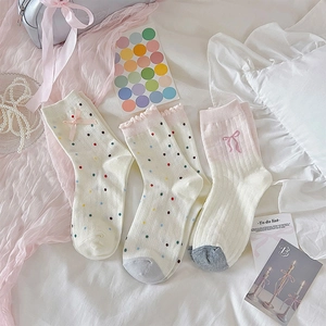 Detalle de tres calcetines japoneses de algodón con lazos rosas y lunares de colores