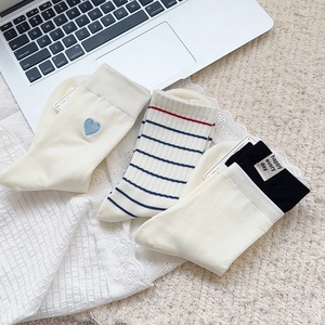 Detail of three cotton socks with blue heart embroidery, stripes, and woven label