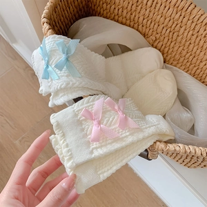Gros plan de chaussettes en tricot blanc avec de délicats nœuds roses et bleus à pois