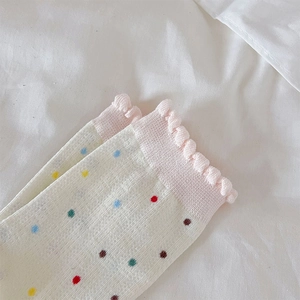 Primer plano de bordes con volantes rosas y lunares de colores en calcetines de punto