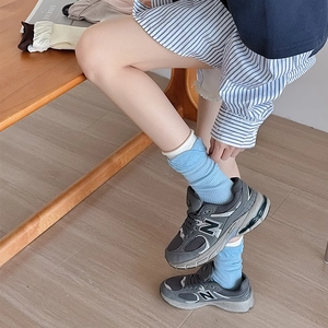 Close-up of blue and white patchwork crew socks styled with grey retro sneakers