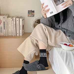 Detail of grey felt clogs with metal buckle paired with geometric patterned mid-calf socks