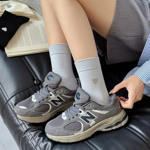 Detail of grey crew socks featuring silver heart embroidery and knitted cotton texture