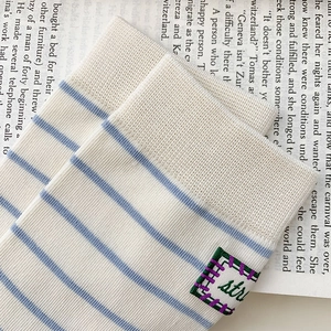 Detail of striped knit socks with fabric label on a decorative book background