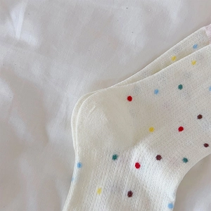 Primer plano de la textura del tejido en calcetines blancos con lunares de colores