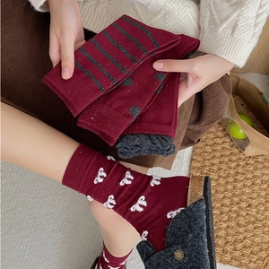 Detailed knit texture of burgundy retro crew socks with stripe and heart patterns