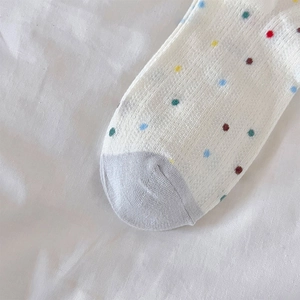 Detalle de estampado de lunares de colores y textura de punto suave en calcetines blancos