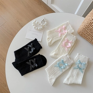 Détail de chaussettes torsadées avec nœuds et bords ondulés en noir et blanc crème