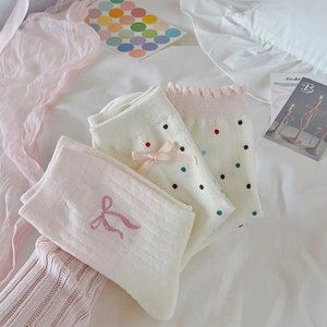 Detalle de calcetines rosa y blanco con bordado de lazo y bordes festoneados en estilo suave