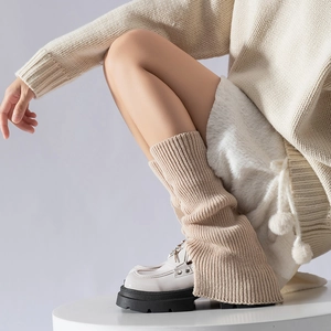 Detail of beige ribbed knit leg warmers with flared hem paired with platform loafers