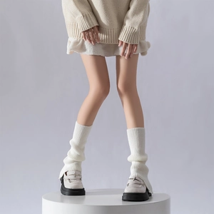 Detail of white knit leg warmers with ribbed texture paired with cream loafers