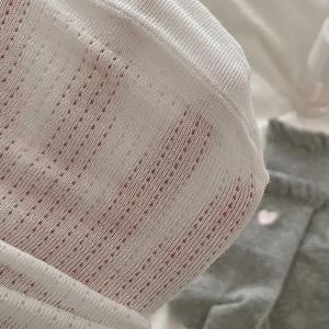 Close-up of white summer socks showing breathable mesh fabric and heart embroidery texture