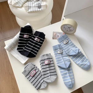Detail of striped cotton crew socks featuring a vintage-style woven label and ribbed texture