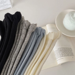 Close-up of stacked ribbed knit crew socks in neutral tones with vertical stripe texture