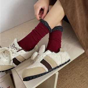 Close-up of red striped knit socks styled with plush shearling sneakers for winter
