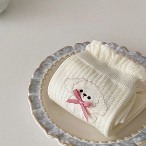 Detailed knit of cream socks with ruffled cuffs and cute puppy pattern with red bow