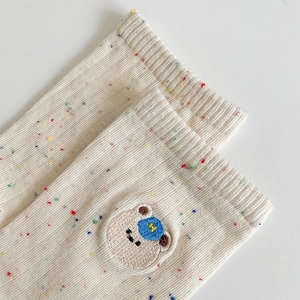 Close-up of beige confetti yarn socks featuring cute bear embroidery and ribbed cuffs