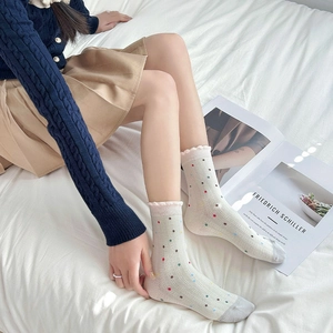 Calcetines de retazos rosa y blanco con lindo lazo y lunares de colores en la cama