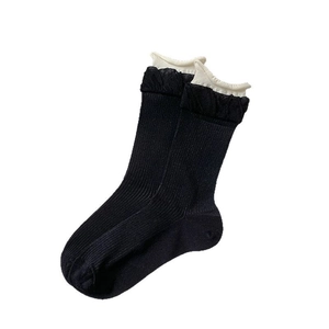 Women's crew socks in black with white ruffled cuffs and vertical ribbed texture