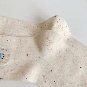 Detail of cream confetti yarn socks with ribbed knit texture and cute bear embroidery