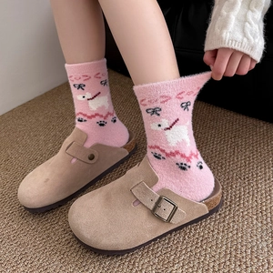 Close-up of pink knitted puppy socks with black bows and brown suede mule slippers