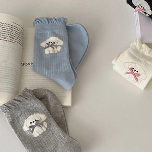 Detail of knit ruffle socks featuring cute puppy embroidery and delicate ribbon bows