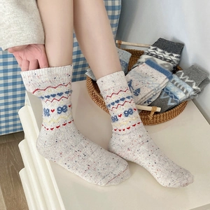 Close-up of Fair Isle wool socks with colorful speckles and knitted heart patterns