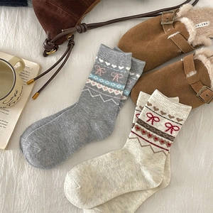 Détail de chaussettes en laine avec motifs de cœurs et nœuds et décor cocooning