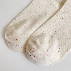 Close-up of beige crew socks with colorful confetti specks and ribbed knit texture detail