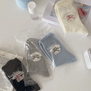 Detail view of four pairs of ribbed knit socks with cute cartoon puppy motifs in soft pastel colors