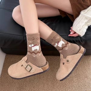 Detail of warm plush socks with cartoon dog pattern and beige suede mule slippers