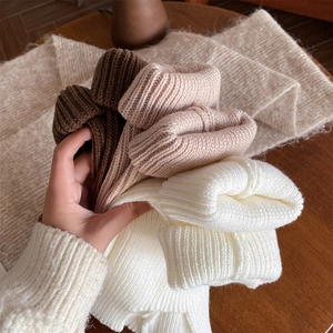 Detailed close-up of thick ribbed knit leg warmers in brown, oatmeal, and white tones