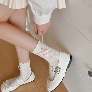 Détail de chaussures Mary Jane blanches et chaussettes à volants avec nœuds roses