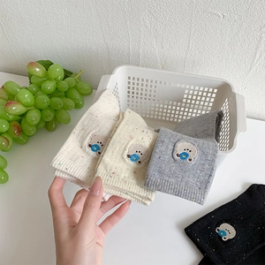 Close-up of crew socks featuring cute bear embroidery and colorful speckled knit fabric